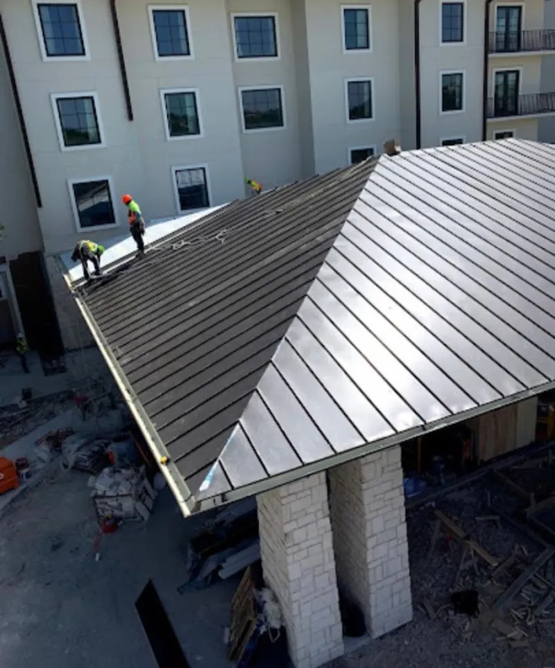 Crew installing standing seam metal roof panels on a commercial project in South Bay